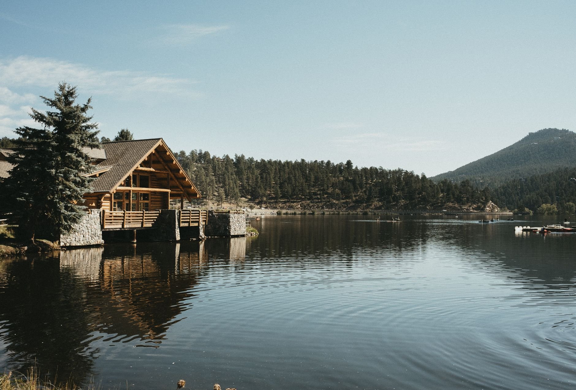 Stunning log cabin by a tranquil lake in Colorado, surrounded by forests and mountains